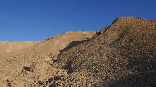 Low angle view of desert against clear blue sky