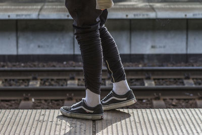 Low section of woman standing on railroad track