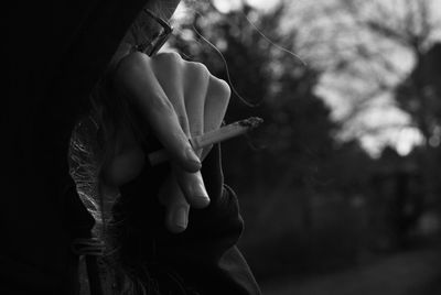 Close-up of man smoking cigarette against trees