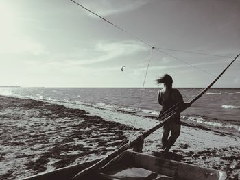 Man fishing at sea shore against sky