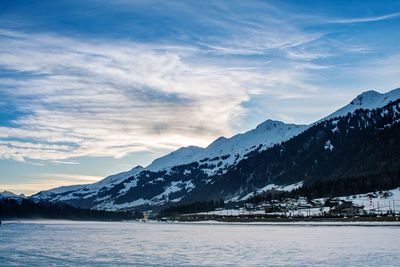 Scenic view of lake and snowcapped mountains against sky during sunset