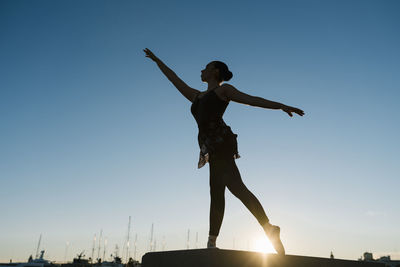 Female ballet dancer practicing during sunset against blue sky