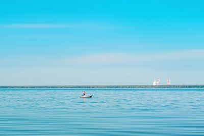 Man in boat in sea against blue sky