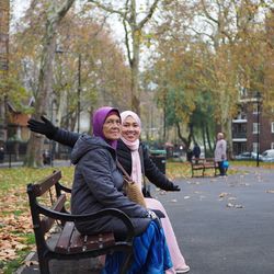 Portrait of woman with mother sitting on bench at park