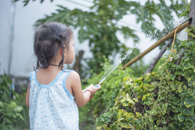 Side view of young woman standing against trees