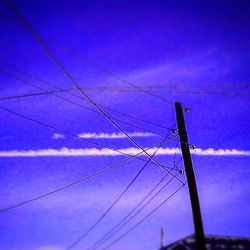 Low angle view of power lines against blue sky