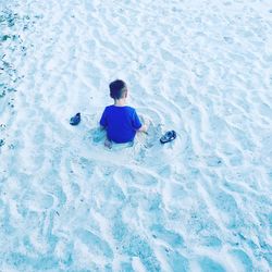 High angle view of boy playing with sand at beach