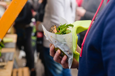 Midsection of person holding hamburger in market