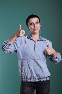 Portrait of young woman standing against blue background