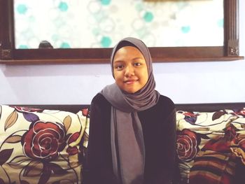 Portrait of smiling girl wearing hijab while sitting at home