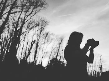 Low angle view of silhouette man using smart phone against sky