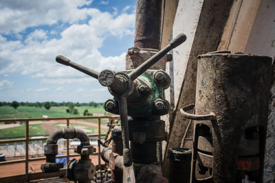 Close-up of old machine part against sky