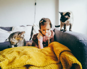 Baby on the couch with her two pets and cats