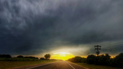 Road by landscape against storm clouds