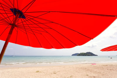 Red umbrella on beach against sky