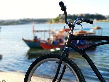 Close-up of bicycle by river against sky