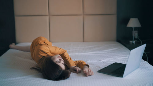 Young woman sleeping on bed with laptop
