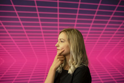 Portrait of woman against pink curtain