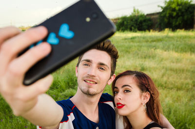 Young couple taking selfie with smart phone on field