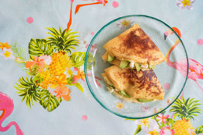 A plate of pancakes with cheese and avocado is on the table with a colorful tablecloth