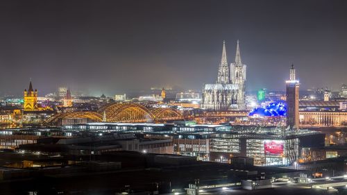 Illuminated cologne cathedral in city against sky at night