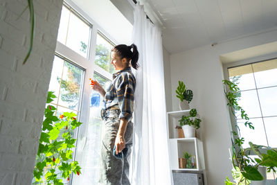 Side view of man standing by window