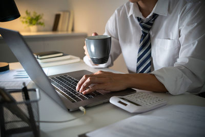 Midsection of woman using laptop on table