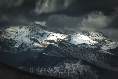 Scenic view of snowcapped mountains against cloudy sky