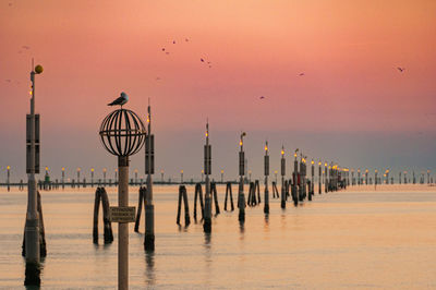 Pier on sea against sky during sunset