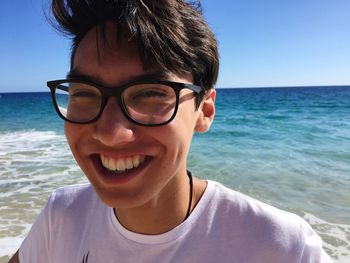 Close-up of young man smiling against water