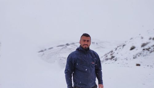 Portrait of man standing on snow covered land