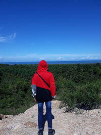 Rear view of man standing on landscape against clear blue sky