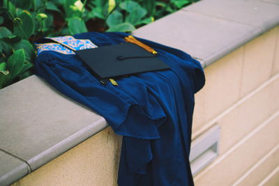 Graduation gown with mortarboard on retaining wall