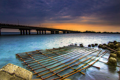 Bridge over river against sky at sunset