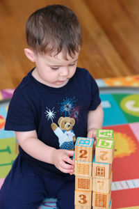 Toddler building a structure out of wooden cubes with alphabet on them