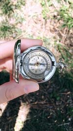 Close-up of hand holding compass over field