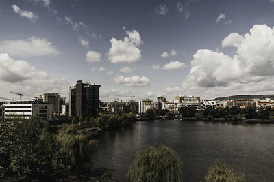 Buildings by river against sky in city