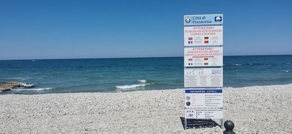 Information sign on beach against clear sky