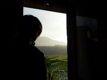 Rear view of woman looking through window