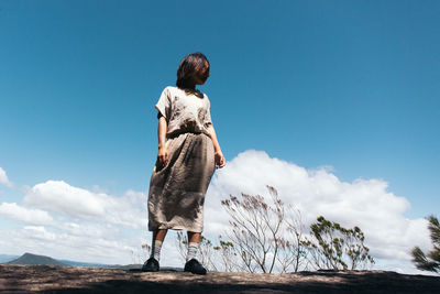 Rear view of woman standing on field against sky