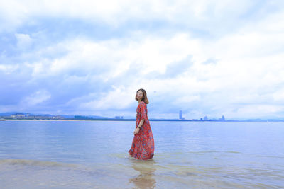 Woman standing in sea against sky