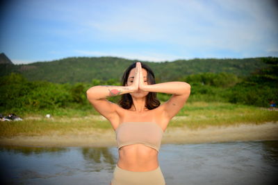 Beautiful woman meditating against sky