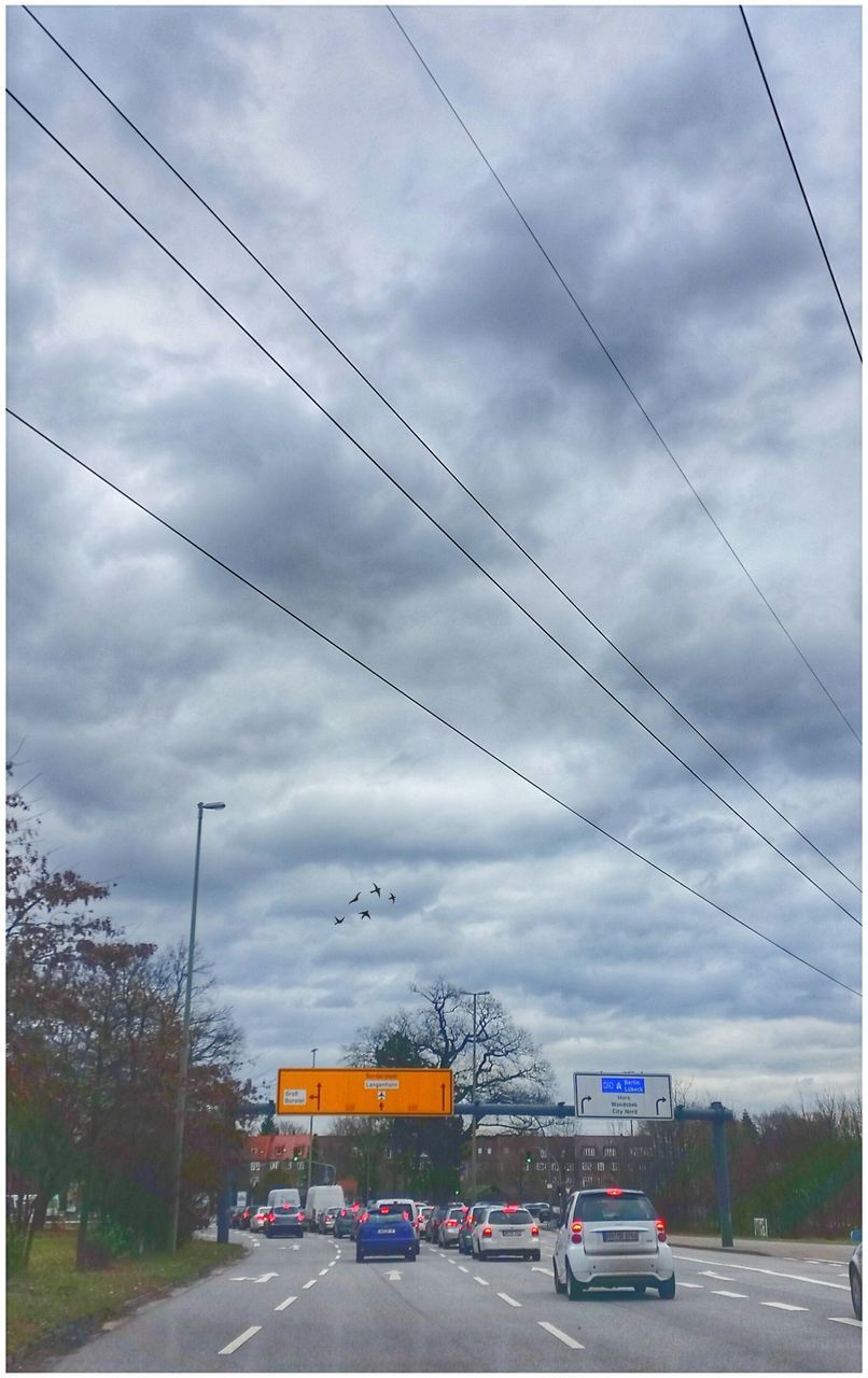 CARS ON ROAD AGAINST CLOUDY SKY