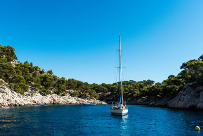 Sailboat sailing on sea against clear blue sky