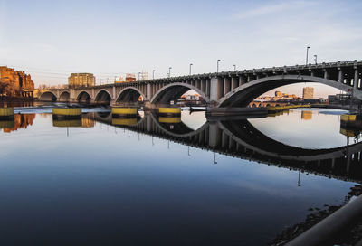 Arch bridge over river in city against sky