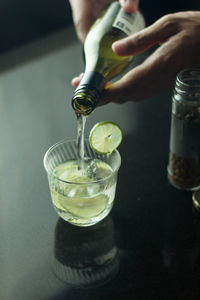 Midsection of person pouring wine in glass on table