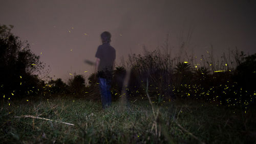 Man standing on field against sky at night