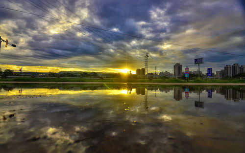 Scenic view of lake against cloudy sky during sunset