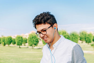 Portrait of young man wearing eyeglasses on field against sky