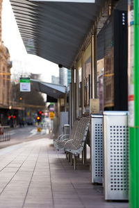 Empty chairs and tables in city against buildings